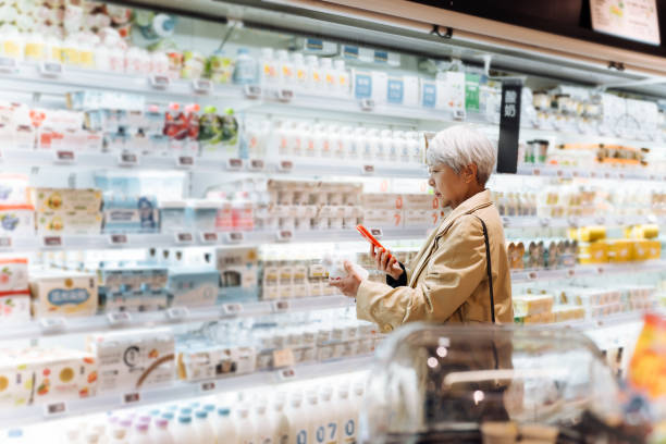 Shopper choosing drinks in a refrigerated supermarket aisle, illustrating functional beverages and dairy products formulated with L-Carnosine